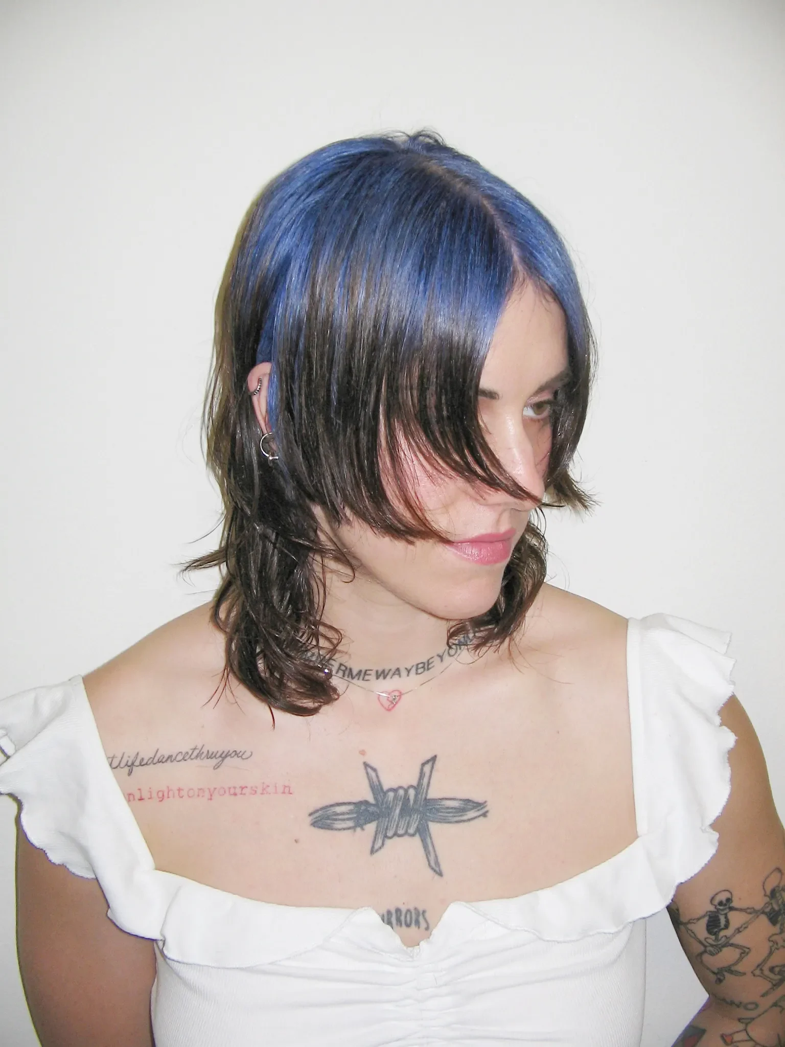 Woman with medium black layered hair and cobalt-blue color across the center-part and crown roots.