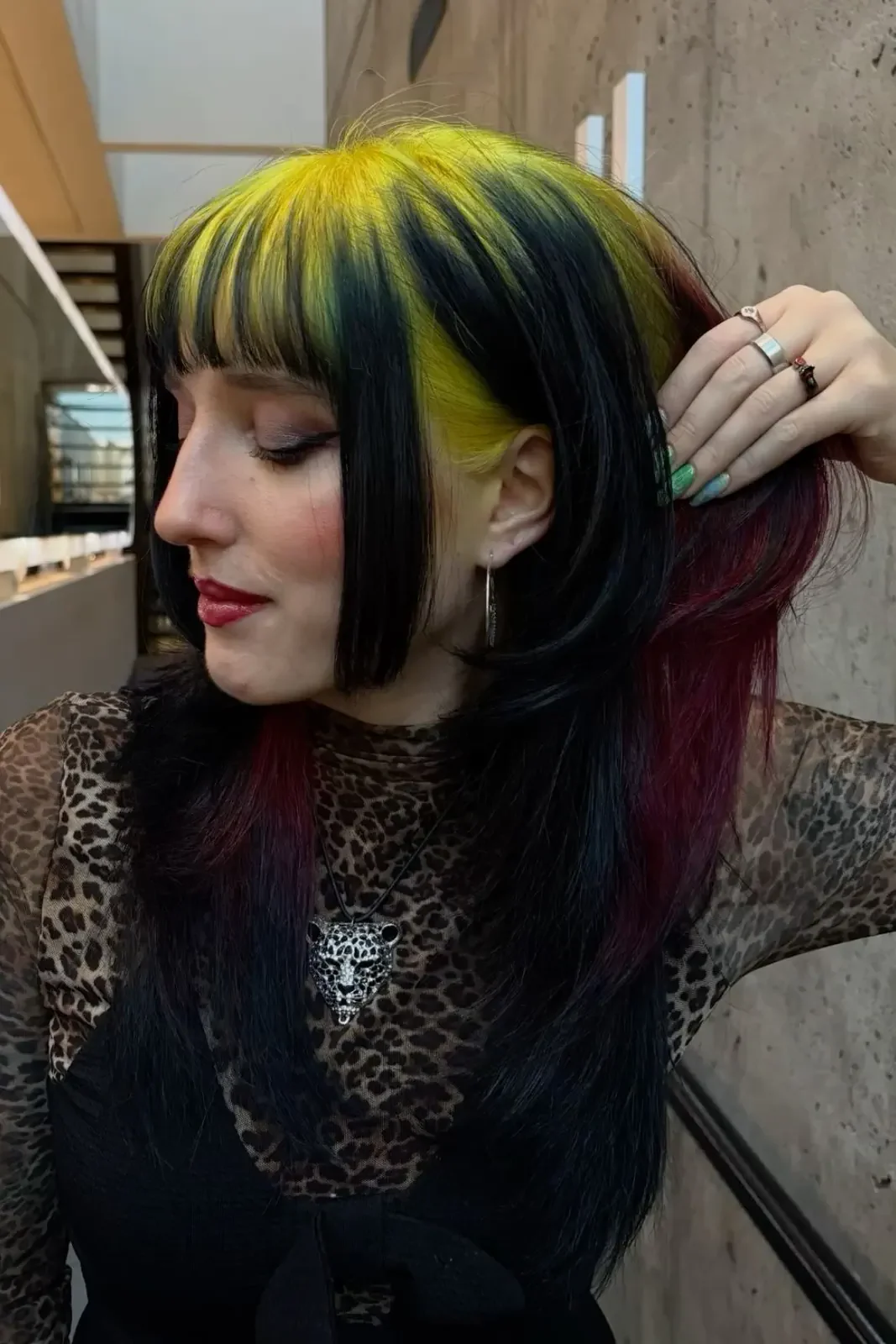 Side profile of a woman with long straight black hair and wide neon-yellow panels beginning near the roots.