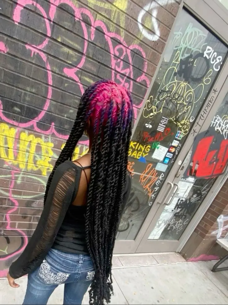 Back view of a woman with long black box braids and magenta-pink color across the crown roots.