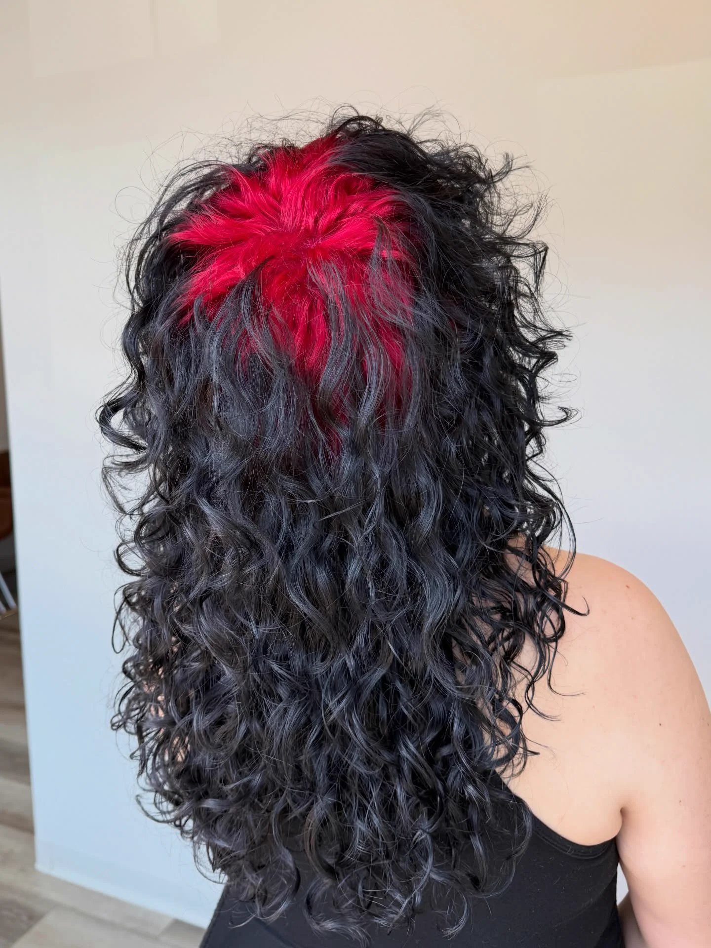 Back view of long black curls with crimson-red color visible through the crown roots.