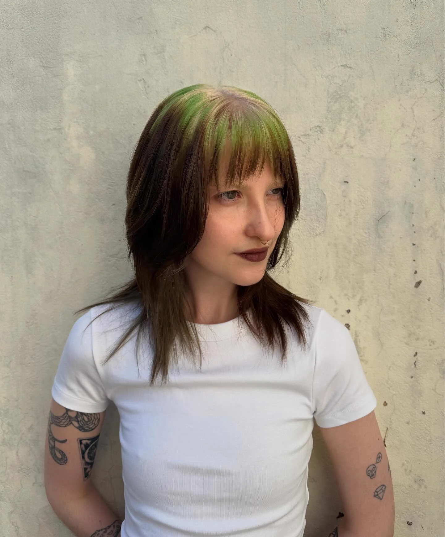 Woman with medium straight brown hair and vivid green color across the top roots and fringe.